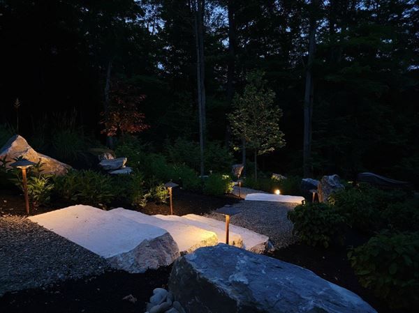 Landscape lighting over stone and plantings at dusk